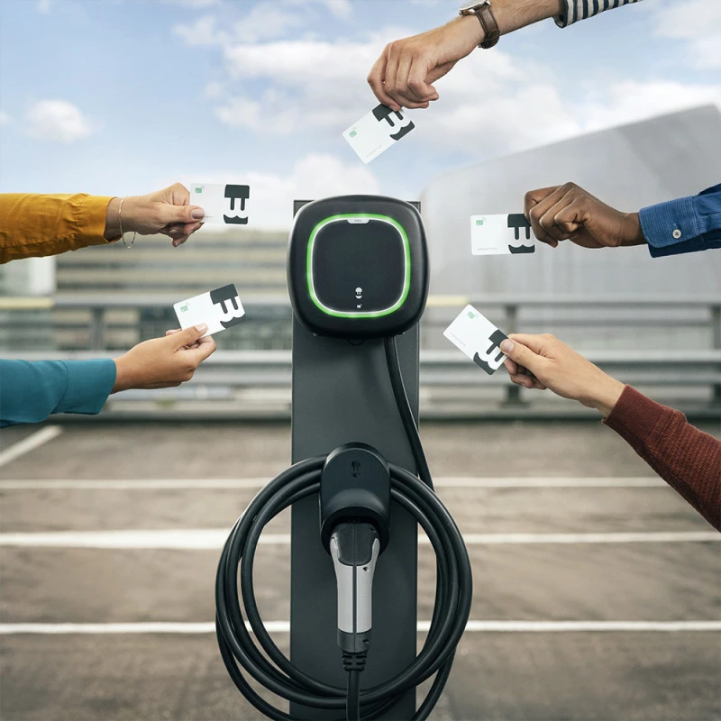 RFID-kártyával indítható elektromos autó töltés modern AC töltőoszlopnál, több felhasználó kezében a kártyákkal.