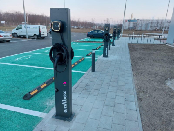 Oszlopos elektromos autó töltőpontok üzleti parkolóban, publikus töltőállomások fizetős üzemeltetése mellett.